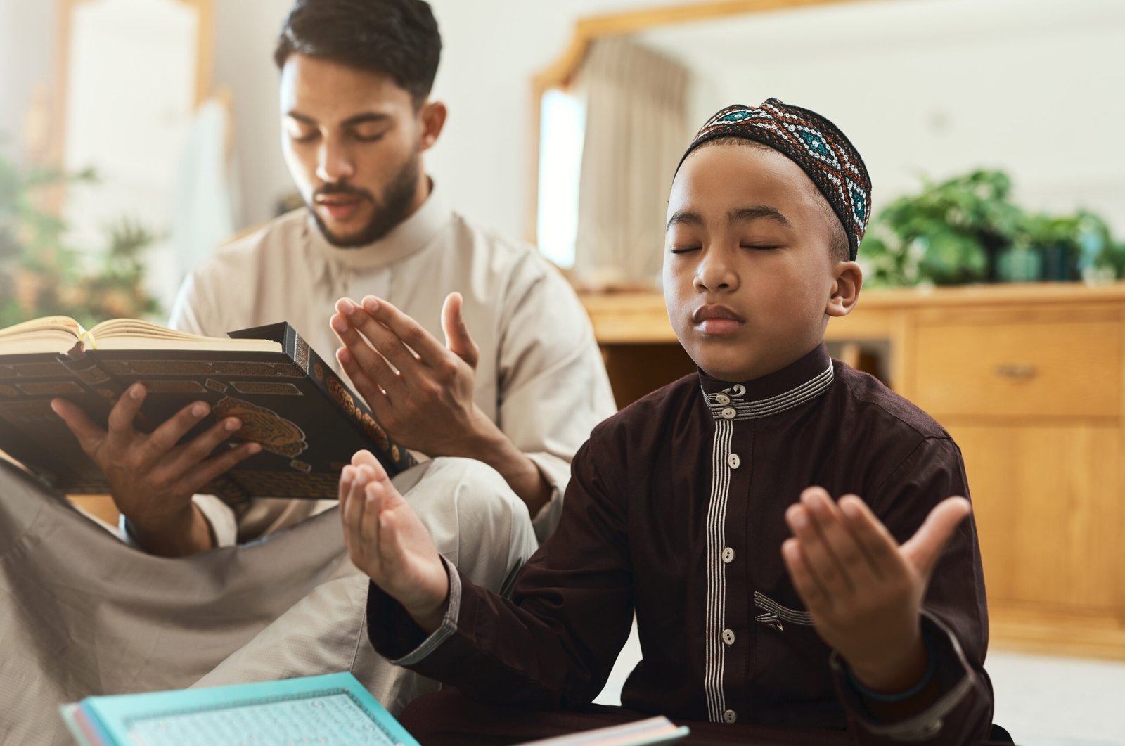 Shot of a young muslim man and his son reading in the lounge at home.